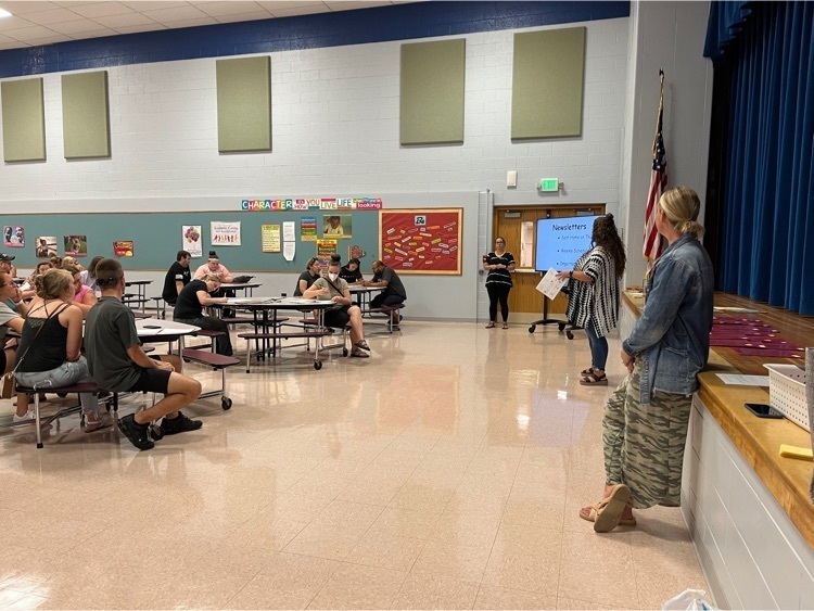 parents and teachers sitting at tables I. the cafeteria .