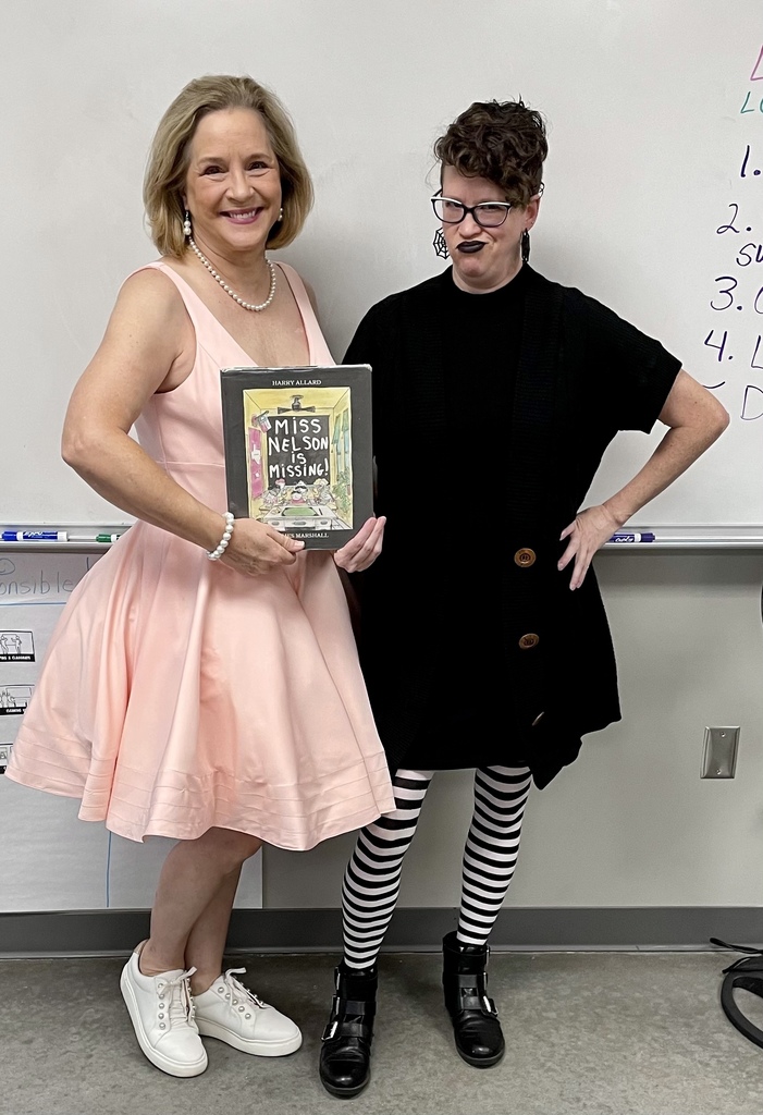 two teachers posing in costume with a book