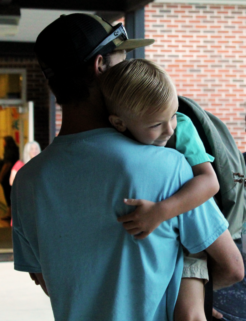 Non-Informative: A little boy holds on to a man before school