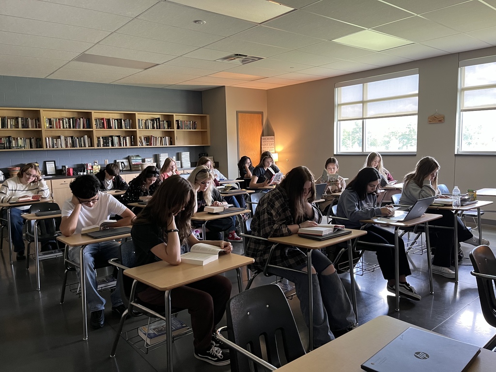 Students sitting at desks in a classroom reading.
