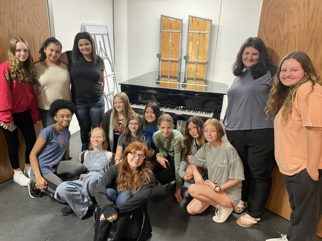 Students posing in front of the piano