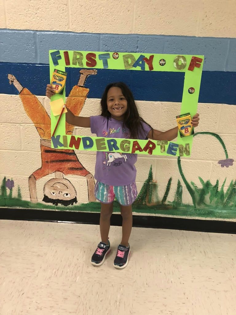 Student holding "First Day of Kindergarten" frame