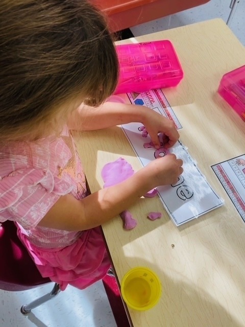 Kindergarten students work on their fine motor skills with playdough.