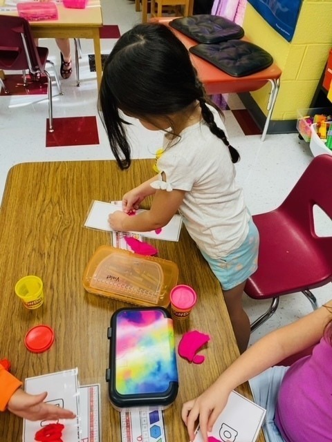 Kindergarten students work on their fine motor skills with playdough.