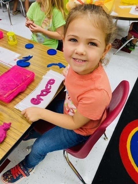Kindergarten students work on their fine motor skills with playdough.