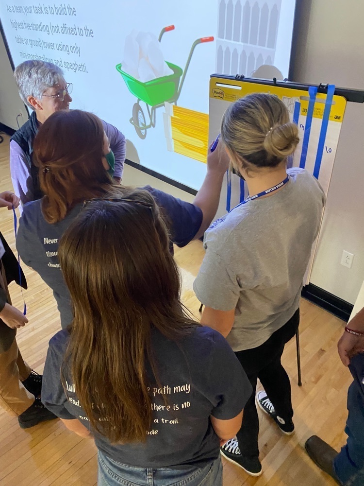 Teammates Tori Gilbert and Adriana Halsey gathered as track-leader Chelsea Harris tallied results from the problem-solving challenge.