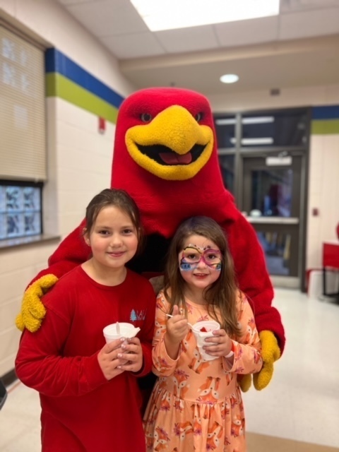 2 girls stand with a mascot
