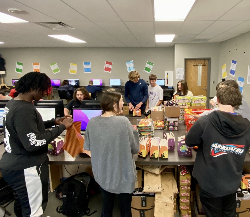several students standing around a table putting candy into boxes
