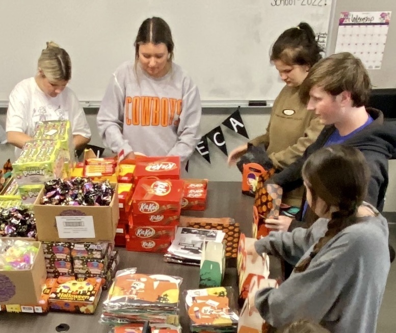 several students standing around a table putting candy into boxes