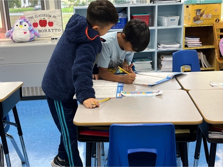 Two students completing math page together.