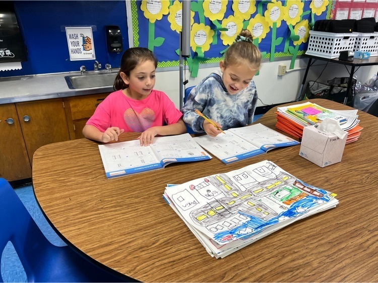 Two students completing math page together.