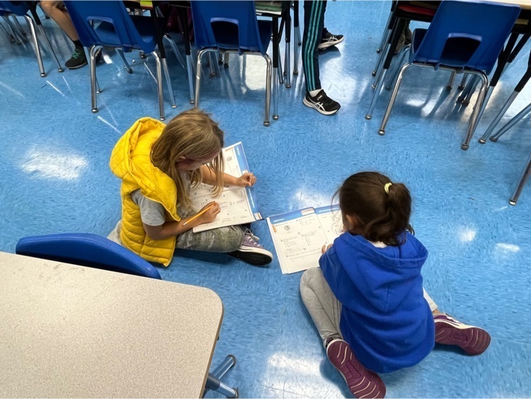 Two students completing math page together.