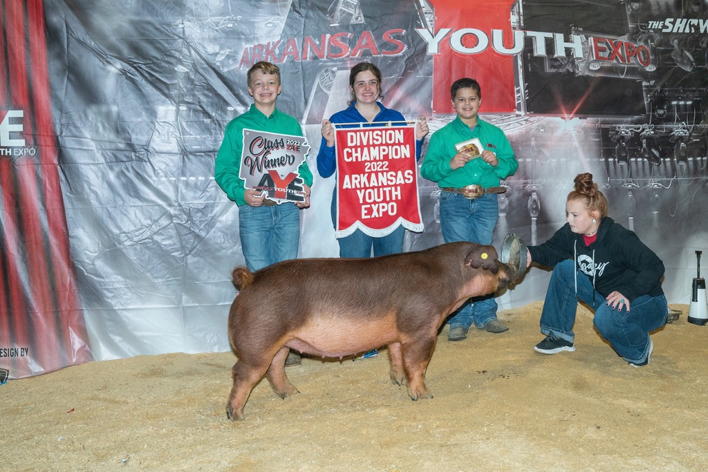 student posing with different pig, family, and winning banners