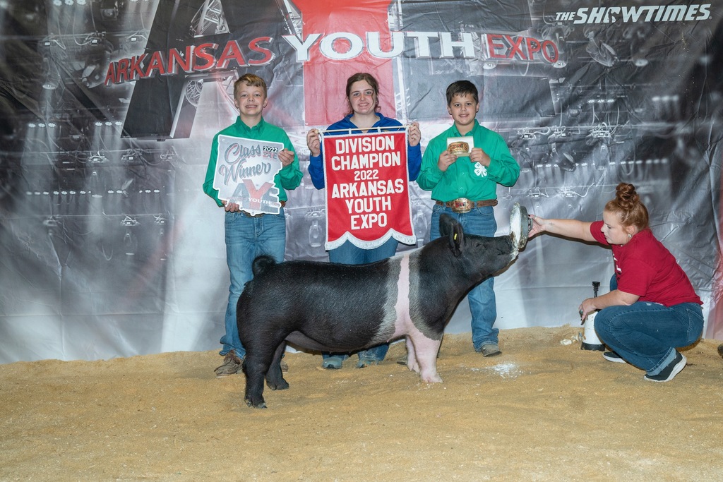 student posing with different pig, family, and winning banners