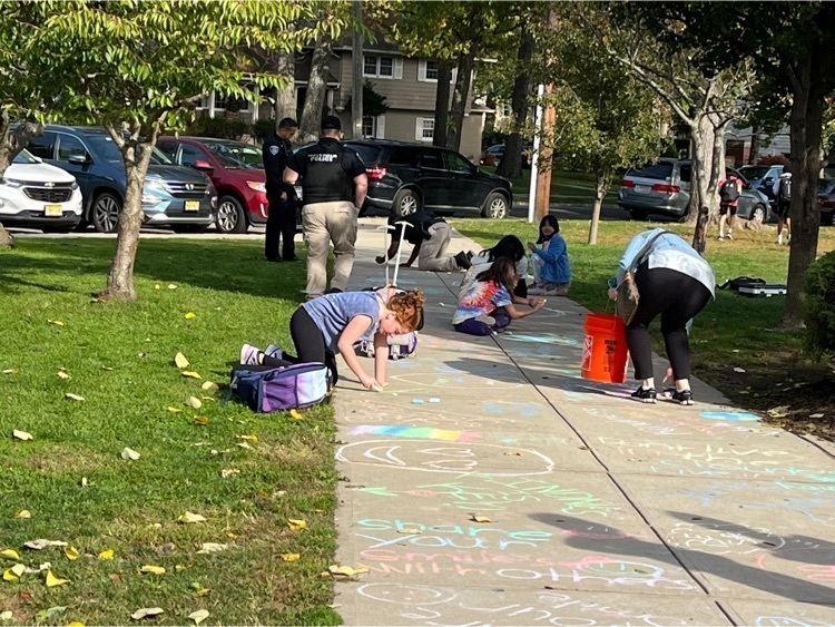 Students, families and police officers draw kind messages on sidewalks. 