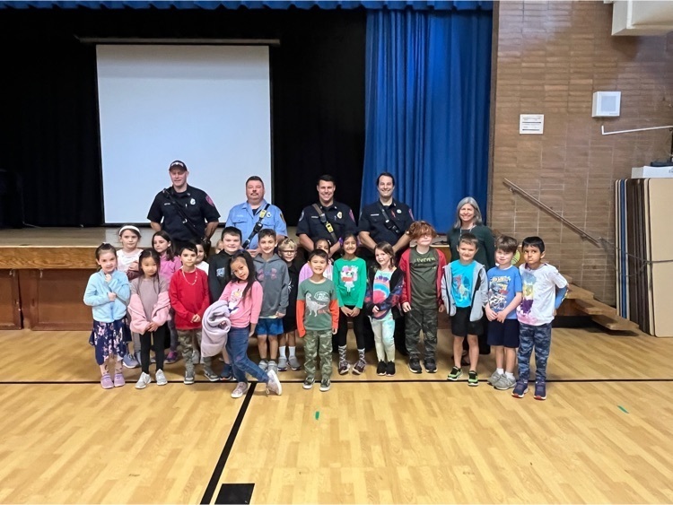 Four firefighters take a group photo with a 1st grade class.