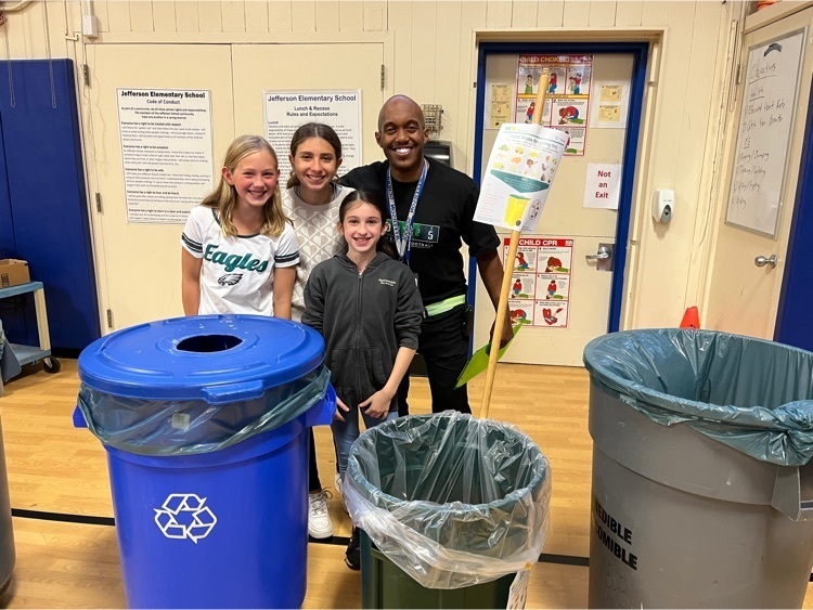 Mr. Thompson and 3 female students posing with the various garbage barrels.