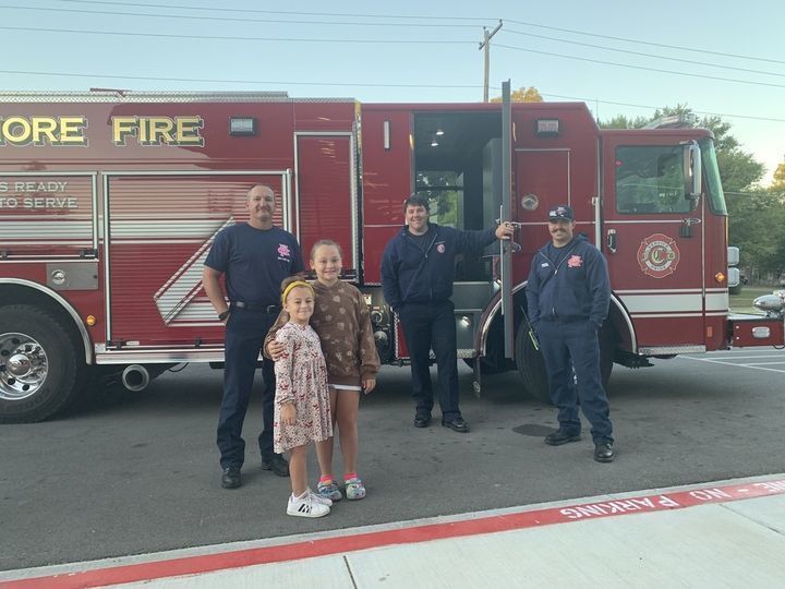 students and firemen in front of firetruck 