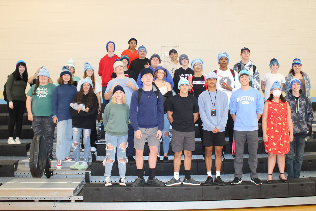 group of students standing, bleachers, blue hats