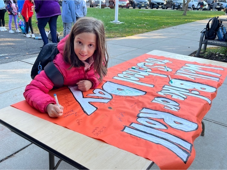 A 4th grade girl signs her name on the walk to school banner.