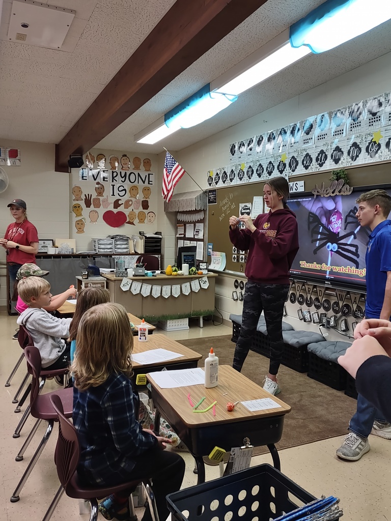 a FFA student stands in front of an elementary class holding up a craft project example