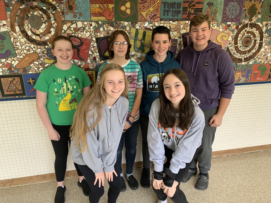 group of students pose in front of artwork