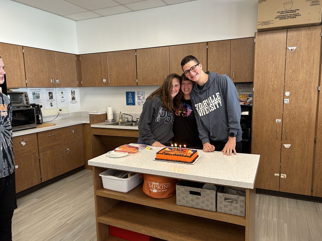 three students pose with birthday cake