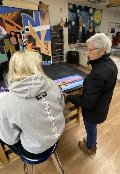 Deb looking at a student’s landscape painting. 