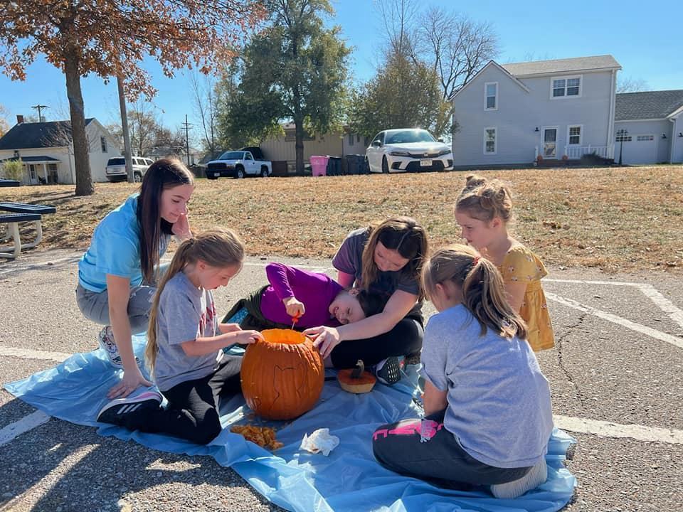 Students carving a pumpkin outdoors