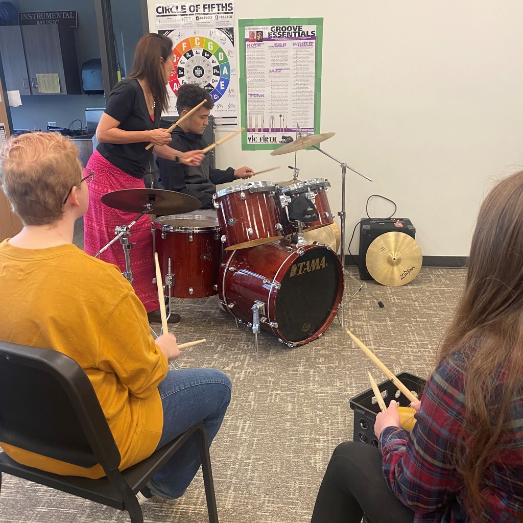 Ms. Bott works with students as they learn to play drums