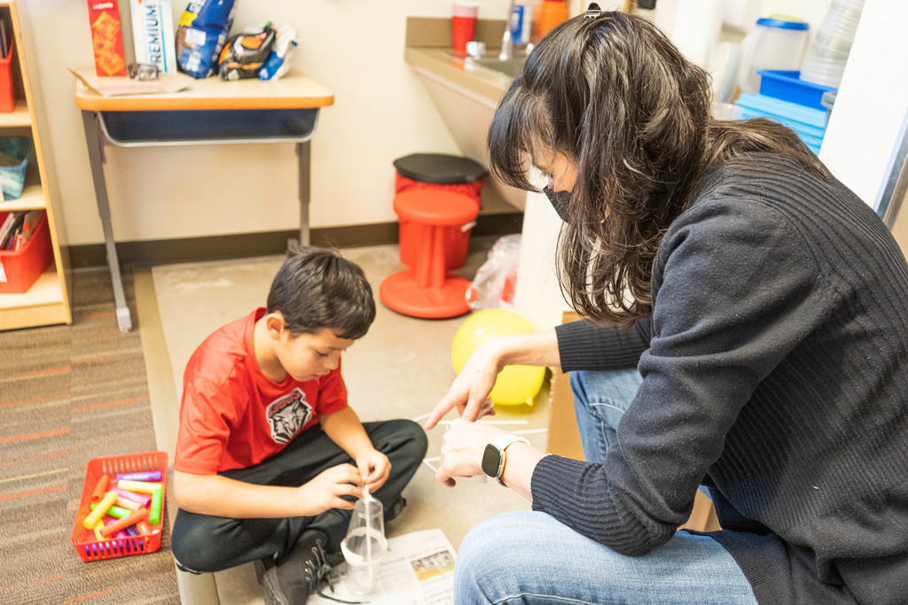 Teacher assisting with child's balloon design