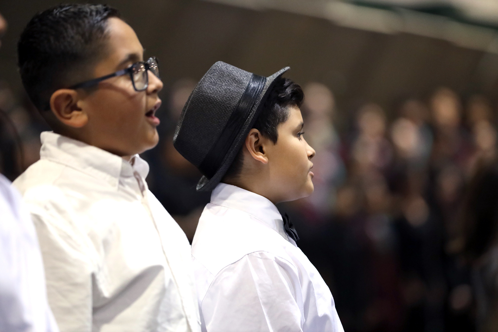 Two young boys in white shirts sing