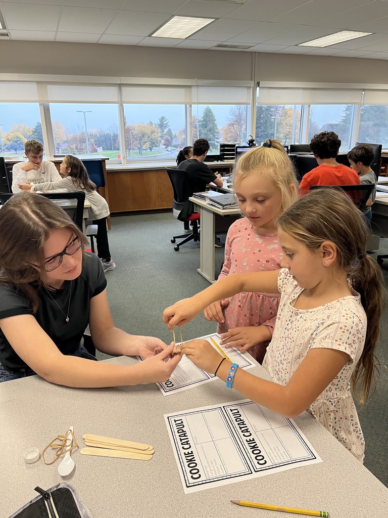 high school student works with two elementary students