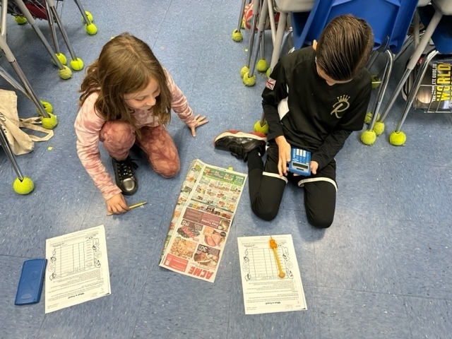 A girl and boy, working on the floor, picking items from a grocery store circular