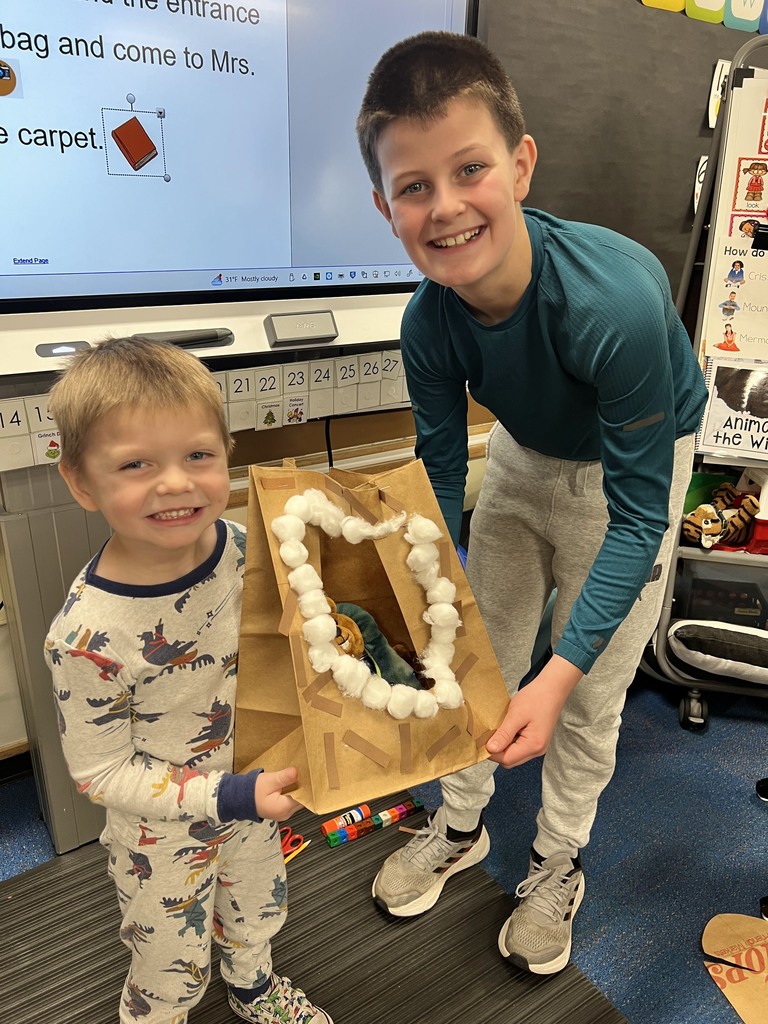 students holding paper bag made to look like a cave for a stuffed animal