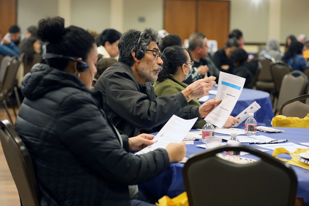 Two audience members seated at a table look at flyers