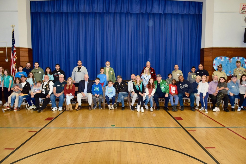 Student and veteran relatives pose for picture in polk street gym