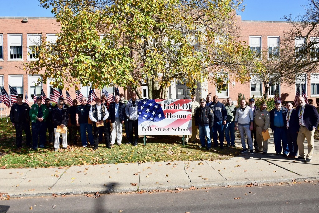veterans pose outside of school thank you sign