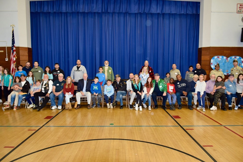 Student and veteran relatives pose for picture in polk street gym
