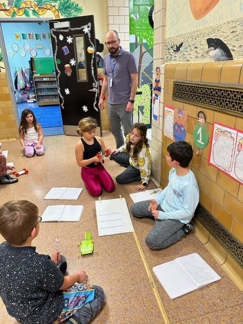 group of students with their teacher working on car investigation, in the hallway