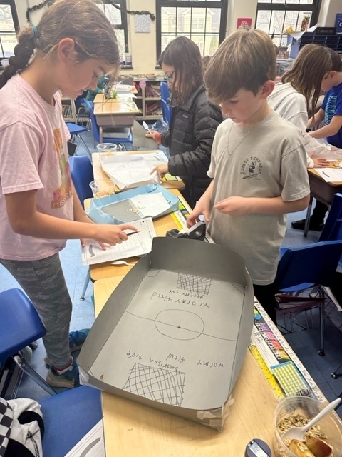 fourth grade girl and boy observing mealworms in their investigation box