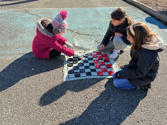 three girls playing checkers during recess