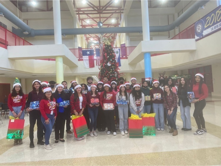 Our National Honor Society students posing in front of a Christmas tree with the toys from their toy drive.