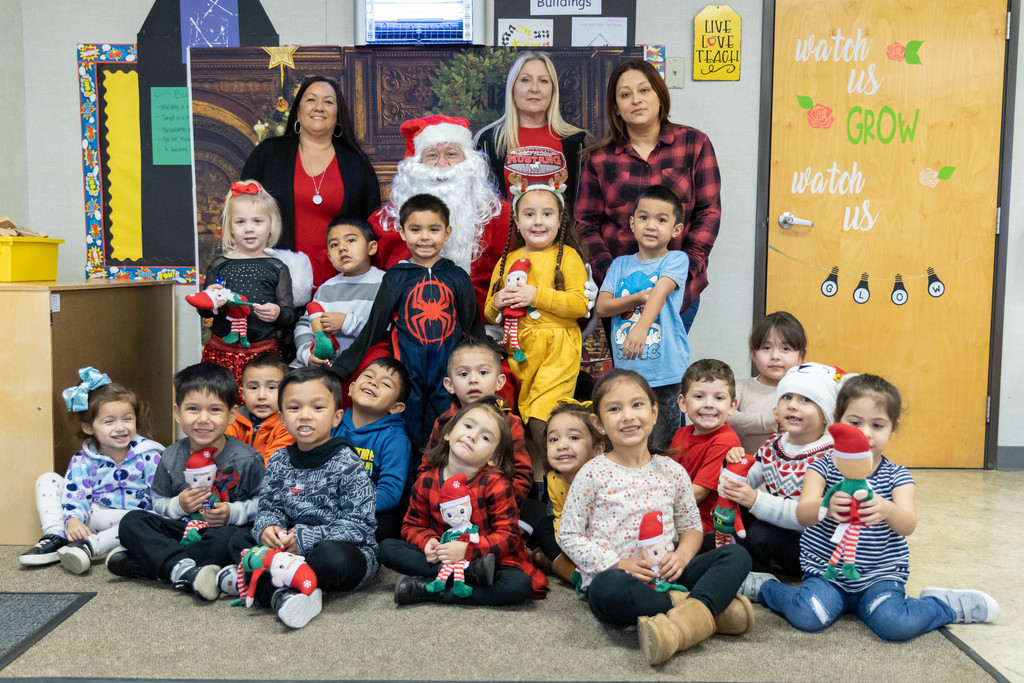 Santa, seated, surrounded by preschool students
