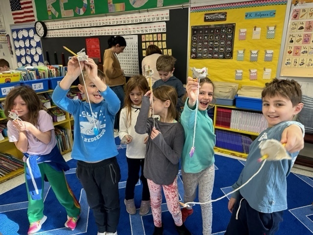 second grade students holding their handmade toys