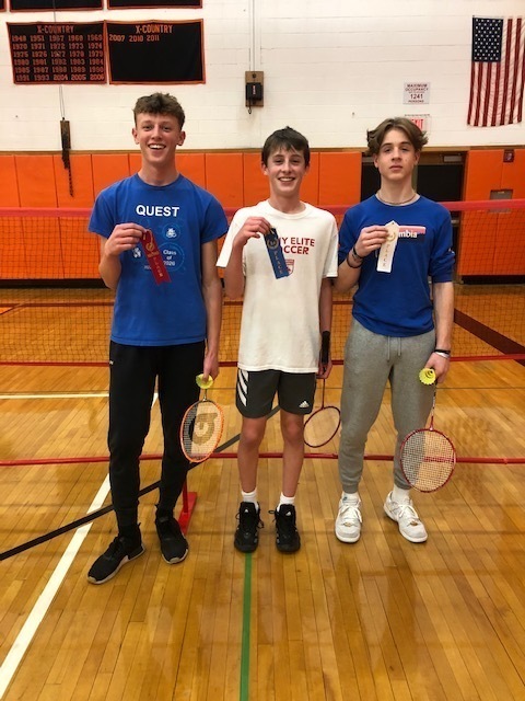 three students with badminton raquets and award ribbons