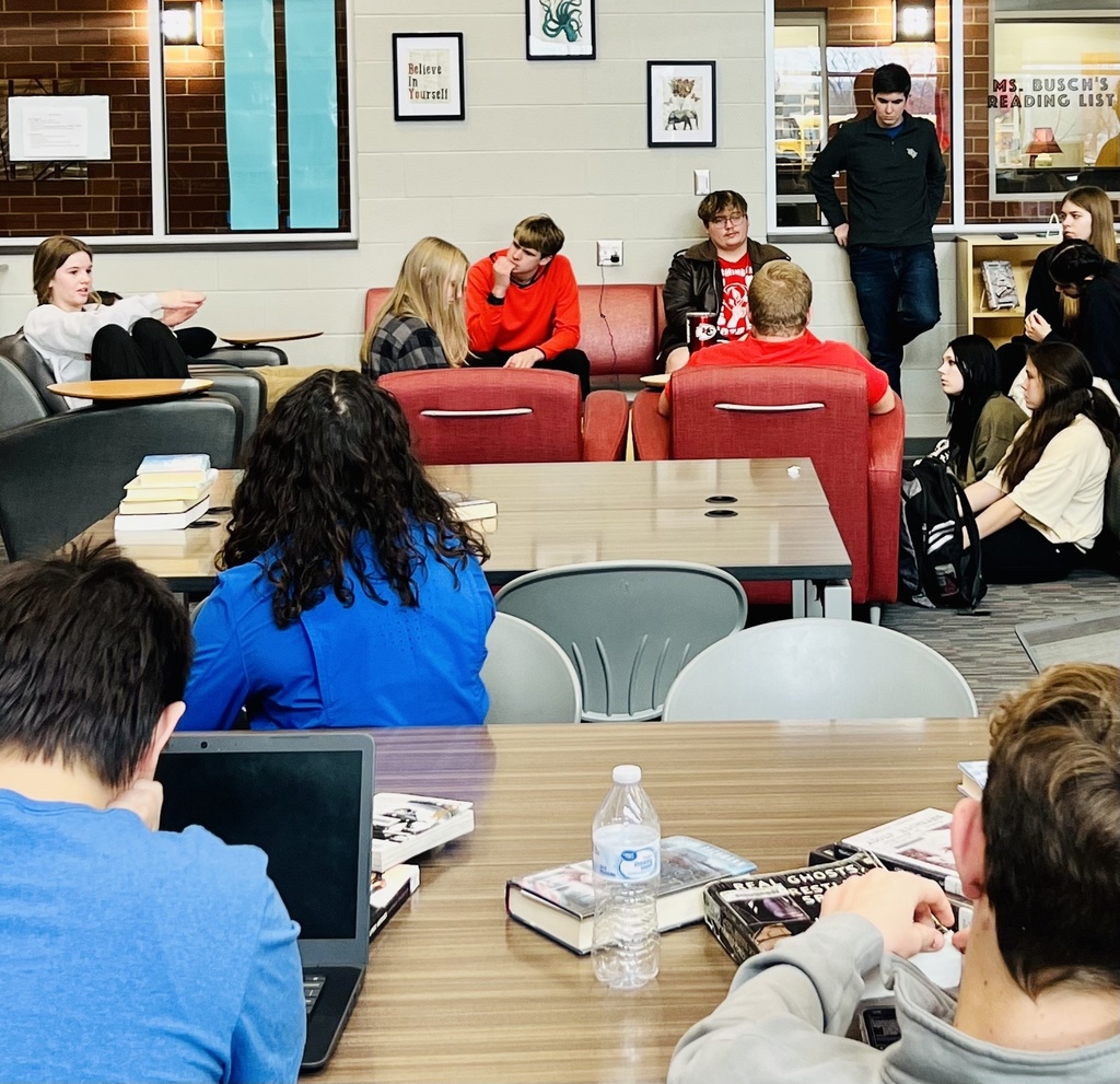 students sitting at tables listening to a student discuss a point