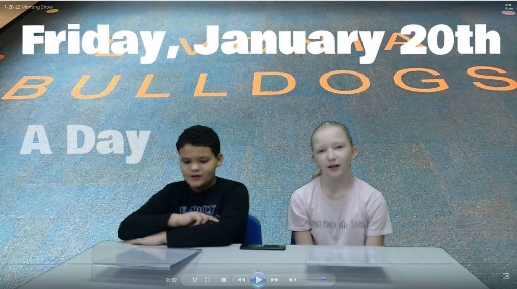 two students at news desk with livonia bulldog carpet