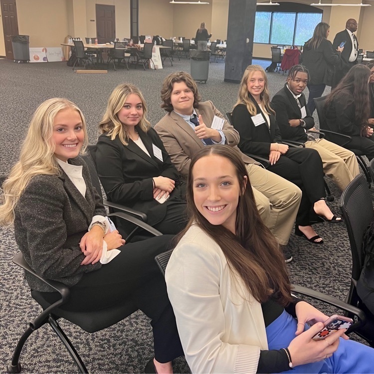 A group of students waiting for awards to start, smiling at the camera.