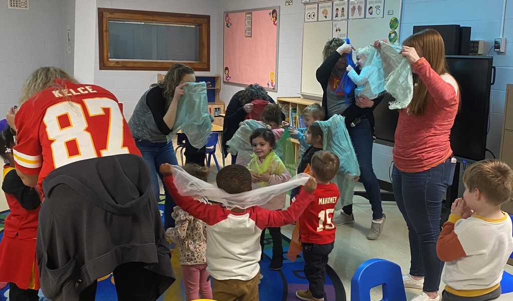 Children and teachers playing with scarves